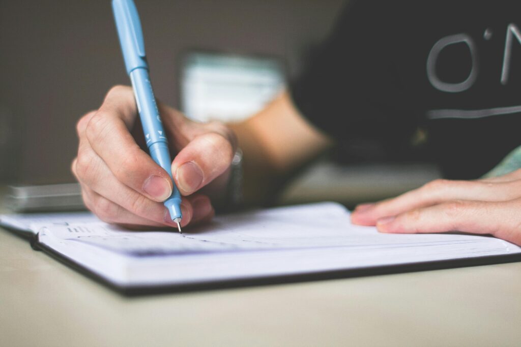 pexels photo 210661 210661 Close-up of hand writing in notebook using a blue pen, focus on creativity.