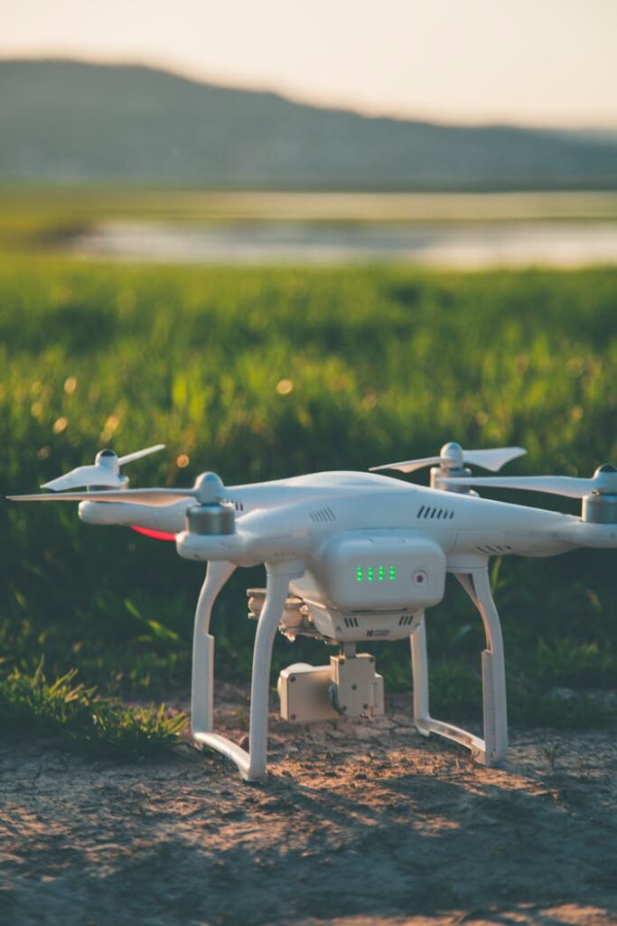 pexels photo 997131 A white drone rests on a grass field during a summer sunset, showcasing technology in nature.
